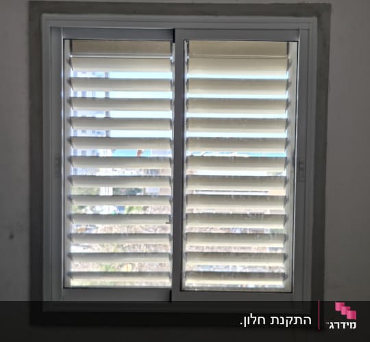 חלון עם תריסי אלומיניום בחדר